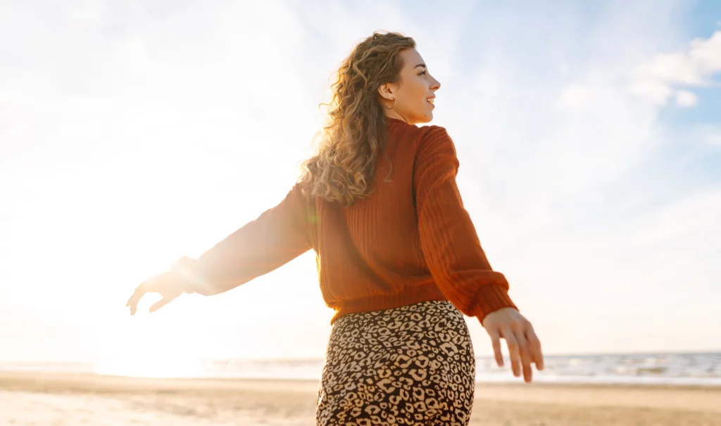 Femme souriante symbolisant l’apaisement et la libération émotionnelle après un accompagnement de coaching bien-être.